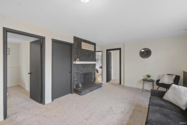 carpeted living area featuring a textured ceiling, a fireplace, and baseboards