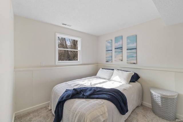 carpeted bedroom featuring baseboards, visible vents, and a textured ceiling