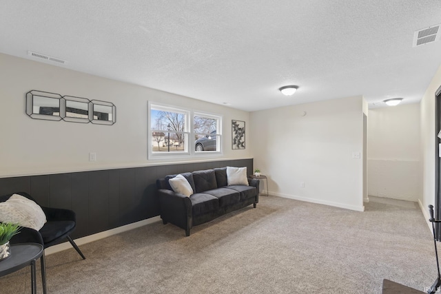 interior space with a textured ceiling, wainscoting, and visible vents