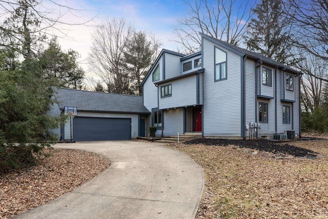 view of front of home featuring a garage, concrete driveway, roof with shingles, and central air condition unit