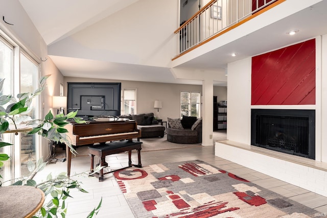 living area with a large fireplace, high vaulted ceiling, and wood finished floors