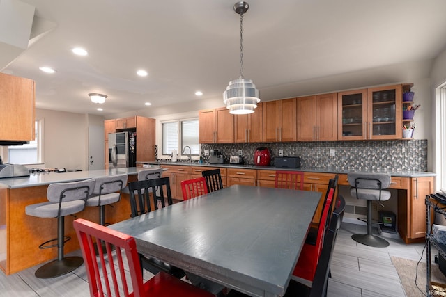 kitchen with decorative backsplash, glass insert cabinets, a breakfast bar area, a peninsula, and a sink