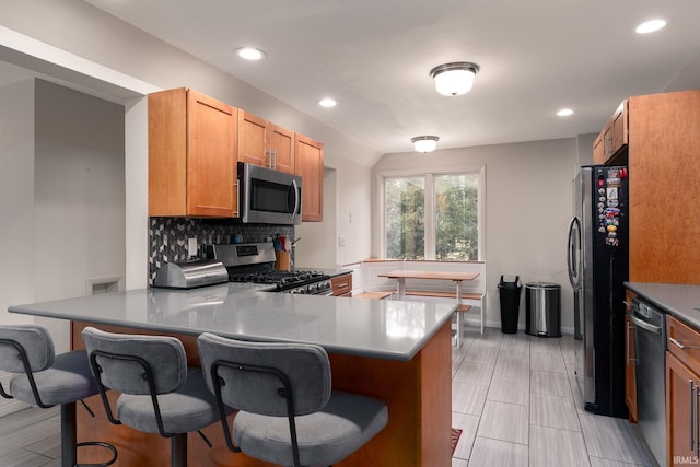 kitchen with stainless steel appliances, recessed lighting, decorative backsplash, a peninsula, and a kitchen bar