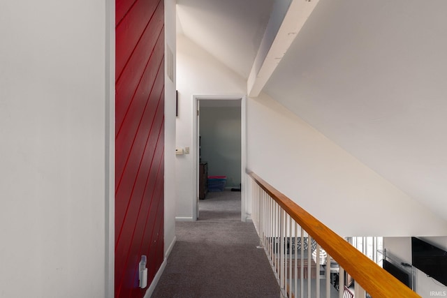 hall featuring carpet floors, baseboards, and vaulted ceiling