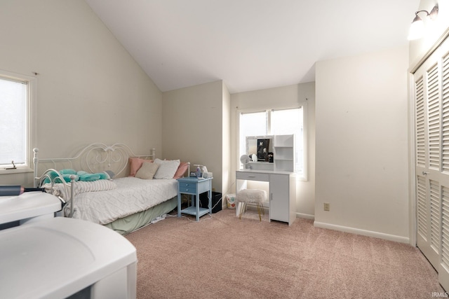 bedroom with lofted ceiling, light carpet, baseboards, and a closet