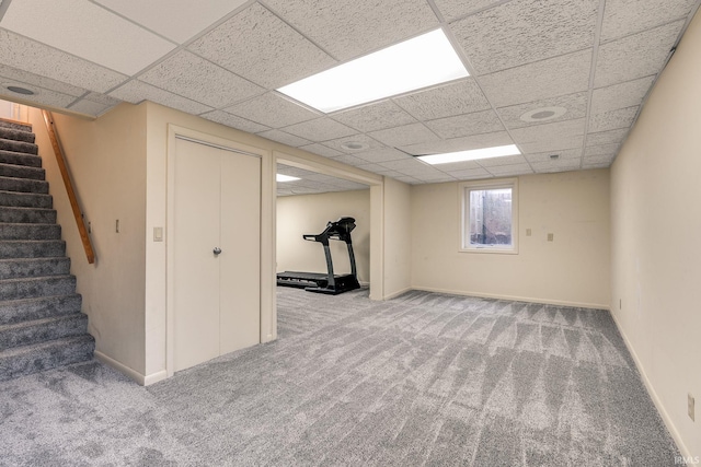 below grade area featuring carpet floors, stairs, baseboards, and a paneled ceiling