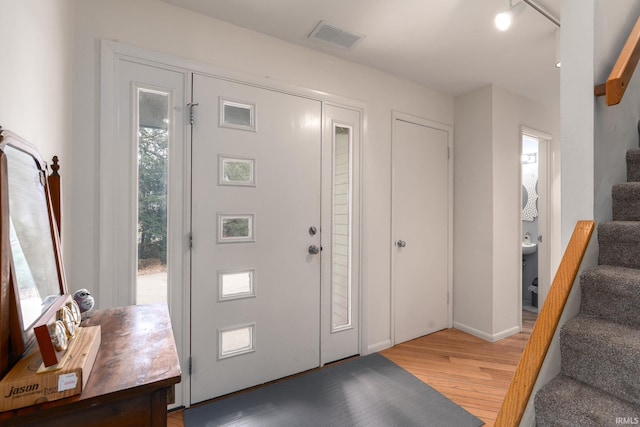 foyer entrance featuring visible vents, light wood finished floors, and stairs