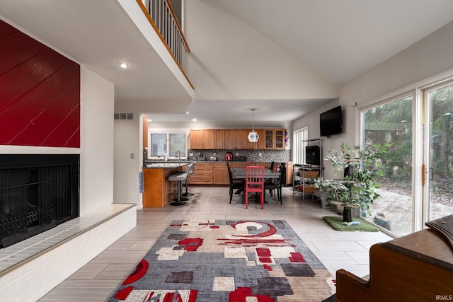 interior space with a large fireplace, high vaulted ceiling, and visible vents