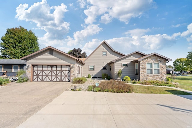 view of front of property featuring a garage, driveway, a front lawn, and stone siding