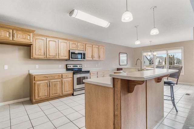 kitchen featuring light tile patterned floors, a sink, light countertops, appliances with stainless steel finishes, and a center island with sink