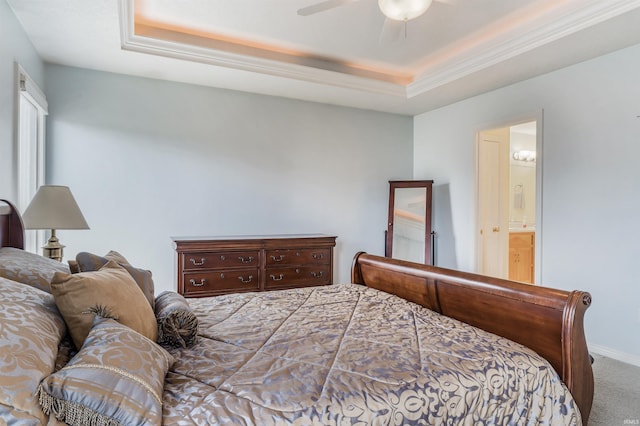 carpeted bedroom featuring ceiling fan, a tray ceiling, connected bathroom, and baseboards