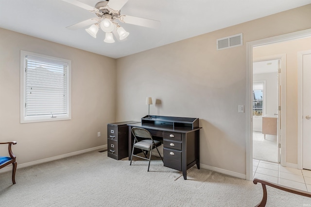 home office with a ceiling fan, light colored carpet, visible vents, and baseboards