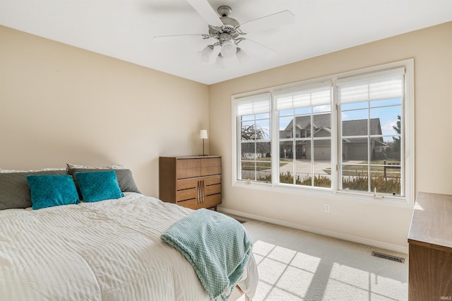 carpeted bedroom with a ceiling fan, visible vents, and baseboards