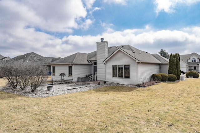 back of property featuring a patio, a yard, a chimney, and a shingled roof