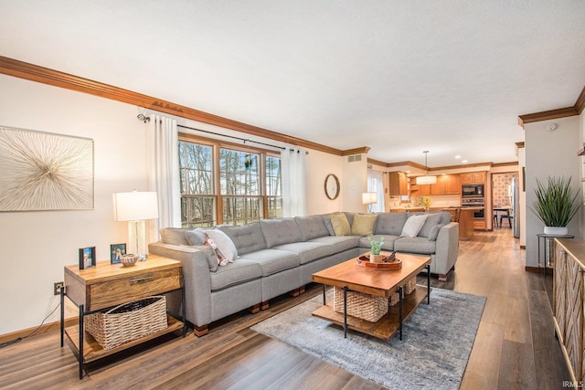 living area featuring ornamental molding, light wood-type flooring, and baseboards