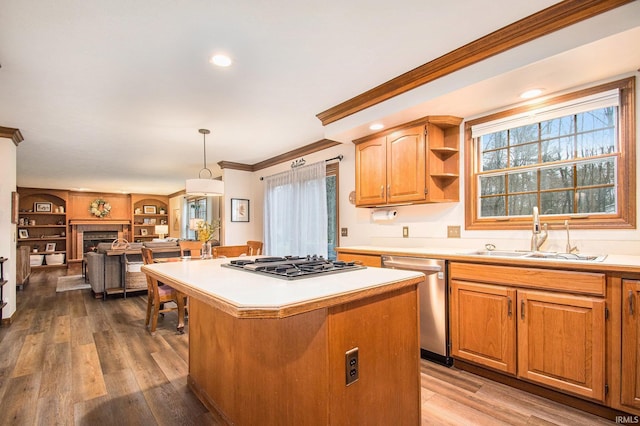 kitchen featuring a center island, stainless steel appliances, crown molding, light countertops, and a sink