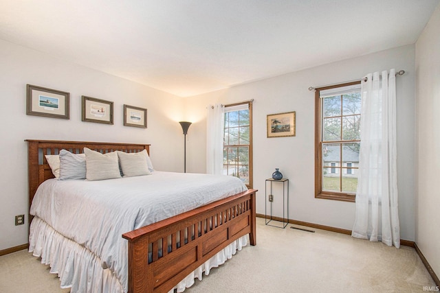 bedroom featuring light carpet, multiple windows, and baseboards