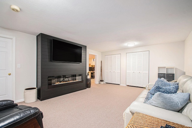 carpeted living area with a fireplace and baseboards