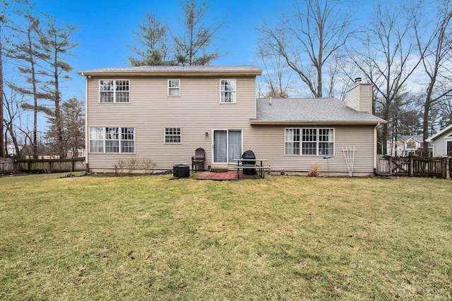 back of property with a yard, a chimney, and fence