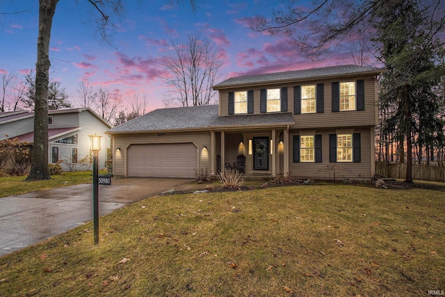 colonial home with a porch, concrete driveway, a lawn, an attached garage, and fence