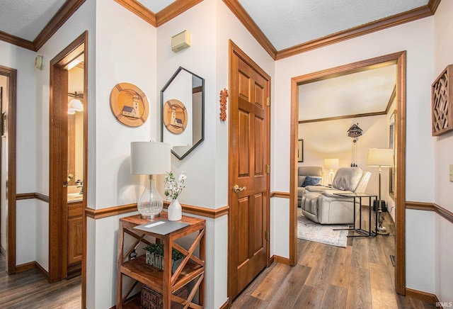 hallway featuring crown molding, a textured ceiling, baseboards, and wood finished floors