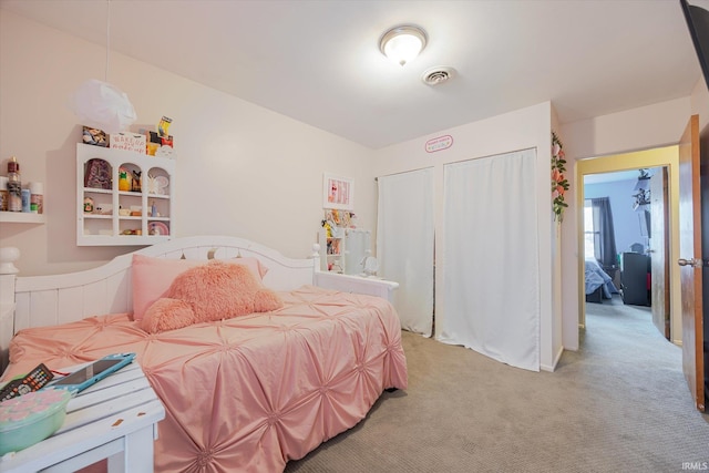 bedroom featuring visible vents, light carpet, and two closets