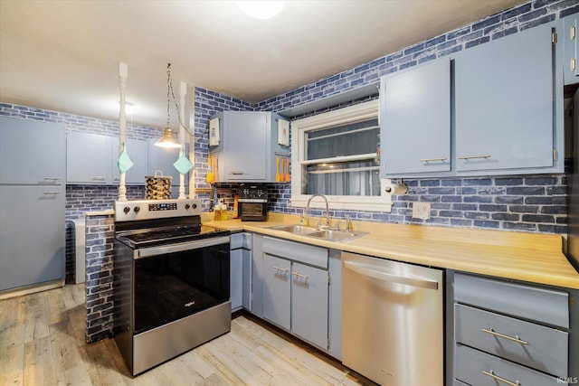 kitchen featuring appliances with stainless steel finishes, light wood-type flooring, light countertops, and a sink