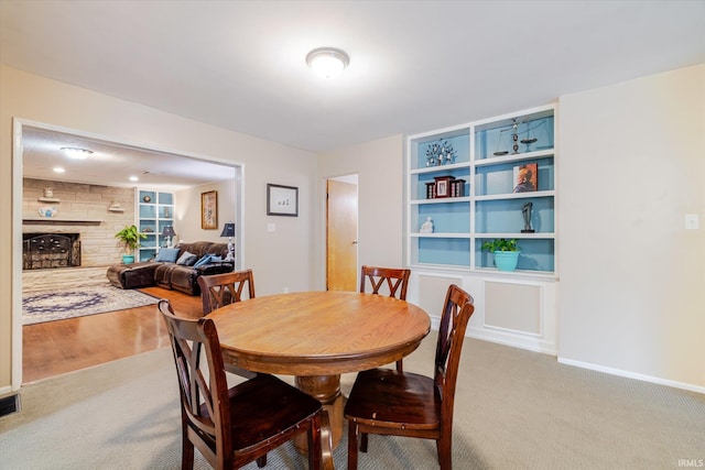 carpeted dining room featuring a fireplace and baseboards