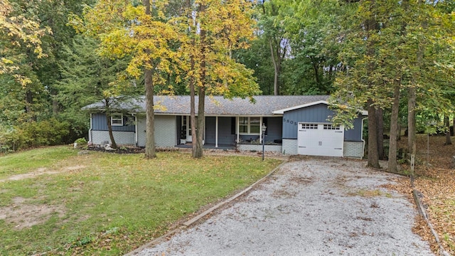 single story home with a porch, an attached garage, brick siding, a front lawn, and board and batten siding