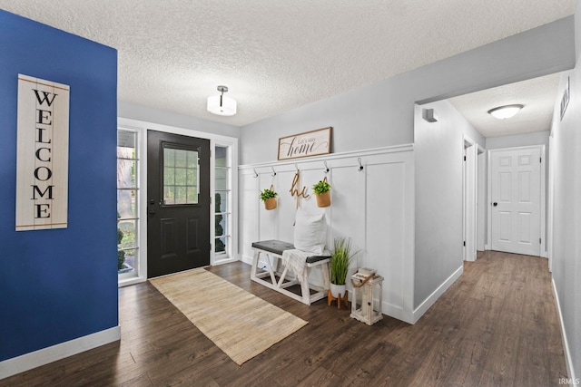 entrance foyer featuring baseboards, dark wood finished floors, and a textured ceiling