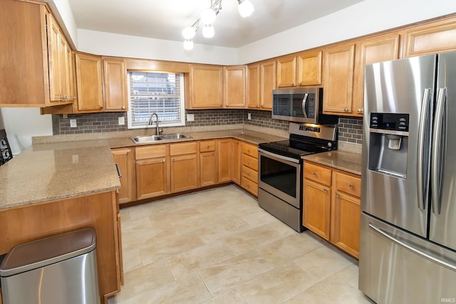 kitchen with stainless steel appliances, backsplash, a sink, and light stone countertops