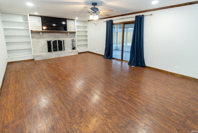 unfurnished living room featuring built in shelves, a fireplace, ceiling fan, wood finished floors, and baseboards