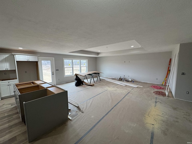 living area featuring recessed lighting, a raised ceiling, and a textured ceiling