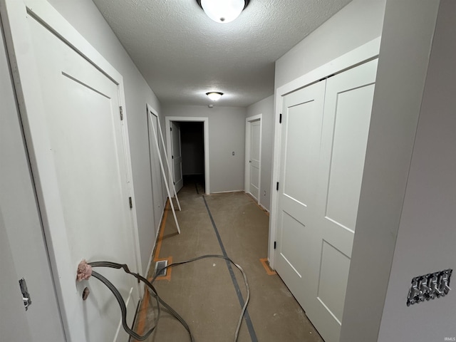 hall featuring concrete floors and a textured ceiling