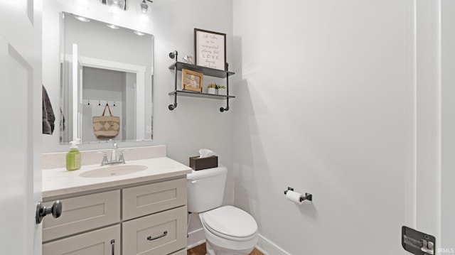 bathroom with baseboards, vanity, and toilet