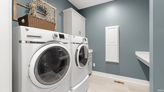 washroom with washer and clothes dryer, light tile patterned floors, visible vents, cabinet space, and baseboards