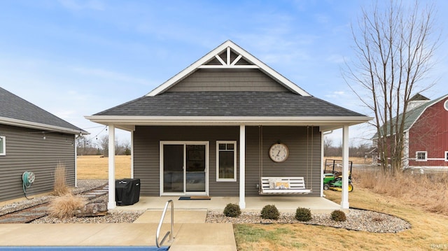 rear view of property with covered porch and a shingled roof