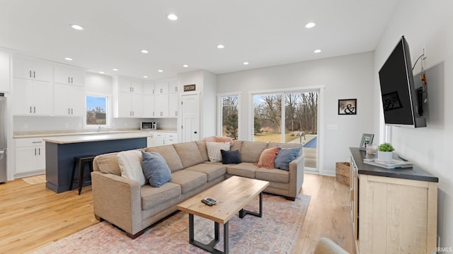 living area with light wood-style flooring, baseboards, and recessed lighting