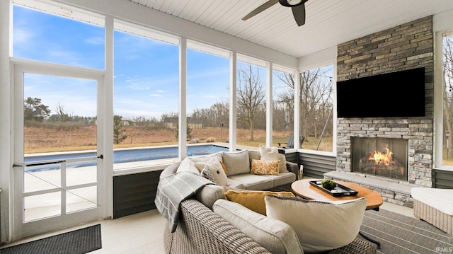 sunroom with a fireplace and a ceiling fan