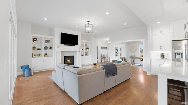 living area featuring light wood finished floors, a glass covered fireplace, and recessed lighting