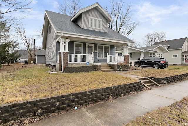 view of front of property featuring a porch, a front yard, and roof with shingles