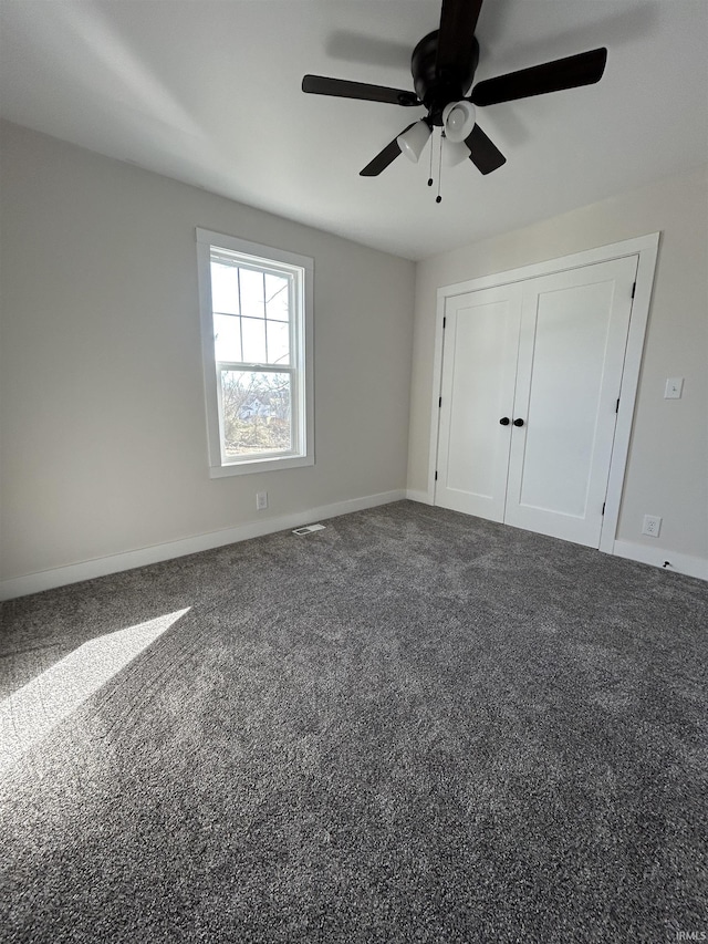 unfurnished bedroom featuring carpet, a closet, baseboards, and a ceiling fan