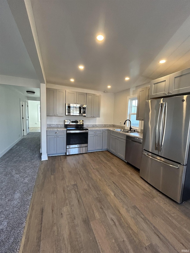 kitchen with dark wood-style flooring, stainless steel appliances, light countertops, gray cabinetry, and a sink