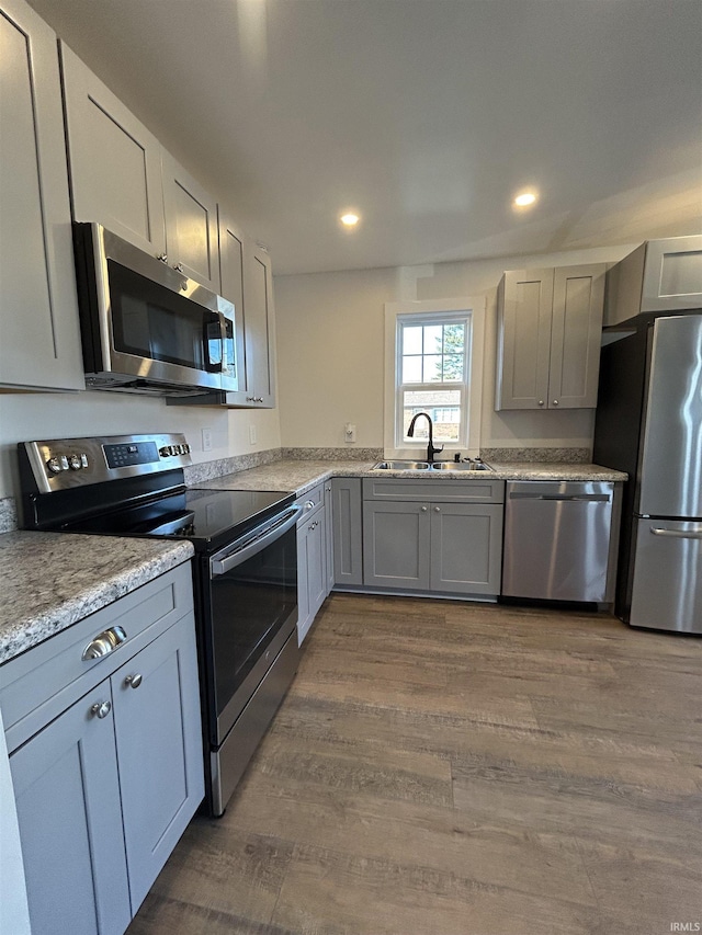 kitchen featuring recessed lighting, wood finished floors, a sink, appliances with stainless steel finishes, and gray cabinets