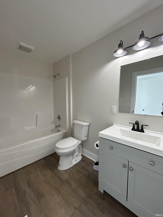 bathroom with toilet, vanity, wood finished floors,  shower combination, and baseboards