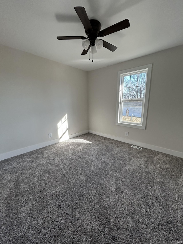 empty room with ceiling fan, carpet floors, visible vents, and baseboards