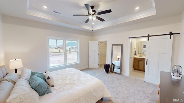 bedroom with a barn door, a raised ceiling, visible vents, and light colored carpet