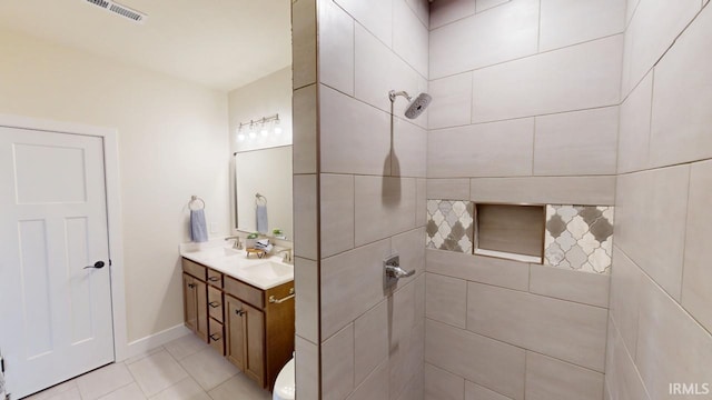 bathroom featuring baseboards, visible vents, tiled shower, tile patterned flooring, and vanity