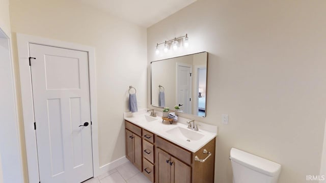 full bath featuring double vanity, toilet, a sink, baseboards, and tile patterned floors