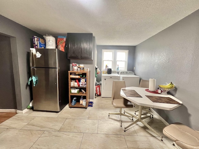 kitchen with a textured ceiling, baseboards, light countertops, freestanding refrigerator, and washing machine and clothes dryer